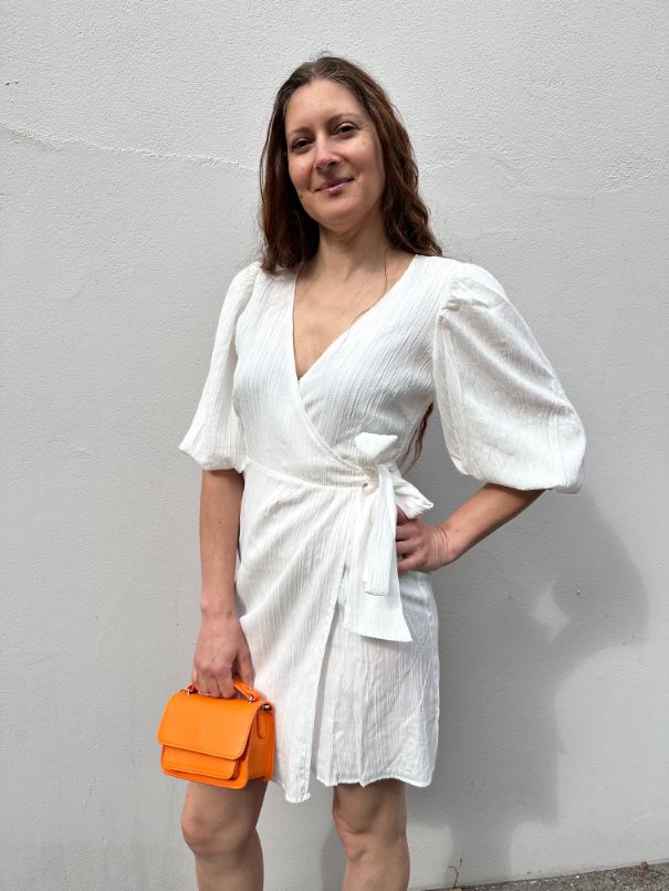 Dovie kjole i fra mbyM, er en sommerlett og fin omslagskjole i en fin hvit farge. Stylet her med orange veske fra Hvisk.